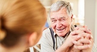 a happy elderly man with dementia holding hands with a female nurse