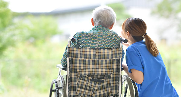 a nurse outside with an elderly person under her care