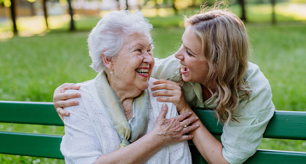 an older lady smiling alongside a younger woman providing companionship to the elderly lady