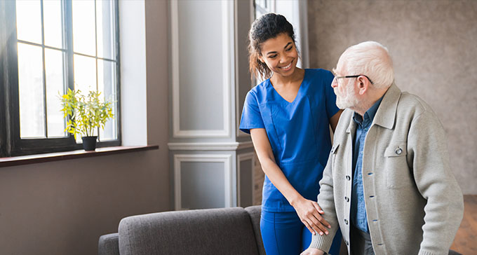 a woman holding the arm of an elderly gentleman a home